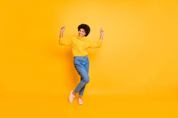 Full length body size photo of curly crazy funny overjoyed girlfriend dancing rejoicing wearing jeans denim sweater footwear isolated over yellow background vivid color - Фото, изображение