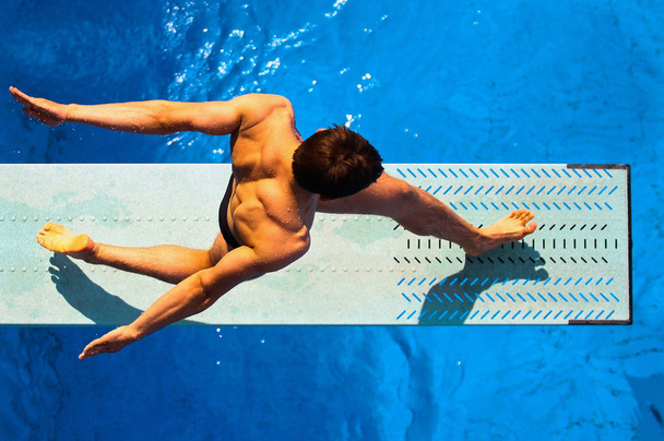 Bovenaanzicht van de duik man tijdens het sporten. Duiker vanuit een uniek perspectief. De atleet wordt gevangen genomen van de top camera bekijken tijdens de praktijk. - Foto, afbeelding