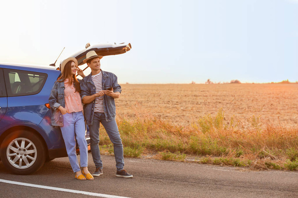 Happy couple near their new car in countryside - Foto, imagen