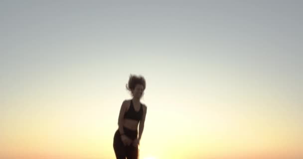 Nainen hyppää trampoliinilla auringonlaskun aikaan.
. - Materiaali, video