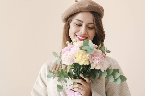 Belle jeune femme avec bouquet de fleurs d'oeillet sur fond clair
 - Photo, image