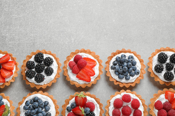 Many different berry tarts on table, flat lay with space for text. Delicious pastries - Fotografie, Obrázek