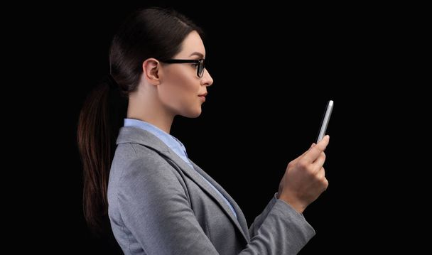 Zakenvrouw met smartphone gezichtsherkenning systeem op zwarte achtergrond - Foto, afbeelding