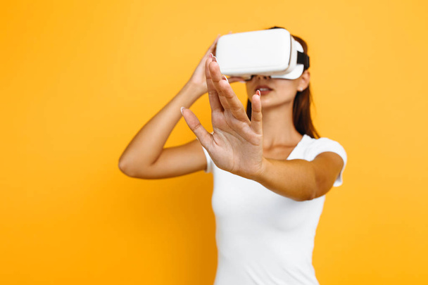 Young beautiful girl in virtual reality glasses on yellow backgr - Fotó, kép