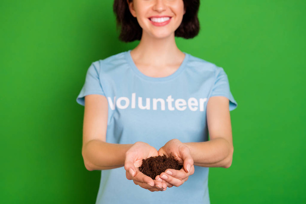 Close-up cropped view portrait of nice attractive cheerful kind girl wearing blue t-shirt holding in hands natural soil rescue save forest isolated over bright vivid shine vibrant green background - Valokuva, kuva