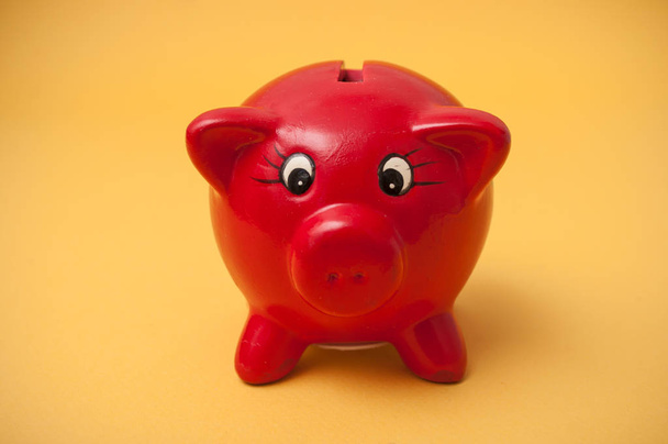 Closeup of red piggy bank on yellow background - Foto, afbeelding
