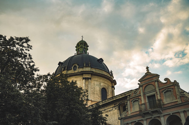 リヴィウウクライナヨーロッパの中世都市劇的な曇りの空の背景に大聖堂古い石ゴシック建築様式のドームの劇的なムーディー写真   - 写真・画像
