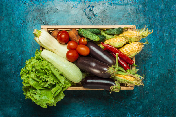 Houten kist met verse groenten op een blauwe stenen achtergrond. Goed oogst concept, natuurlijk product. Platte lay, bovenaanzicht - Foto, afbeelding