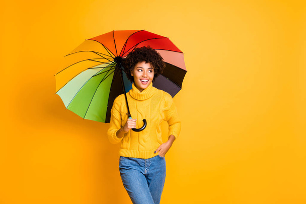 Bad weather but good mood concept. Photo of positive optimistic cheerful shiny person holding hiding under multicolored accessory in hand walking on street in casual jeans isolated bright background - Photo, image
