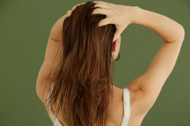 Studio shot of woman applying hair oil with her fingers - Foto, afbeelding