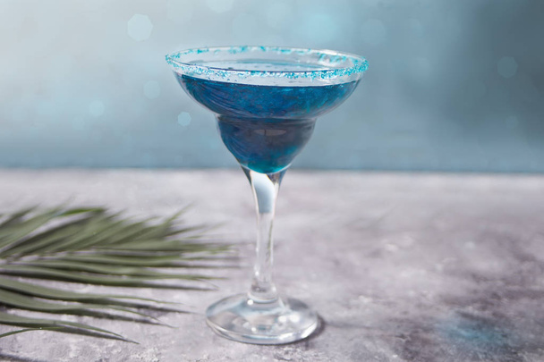 Glass of blue cocktail with the palm leaf on the concrete background. Hawaiian cocktai, lagoon cocktail, curacao. - Φωτογραφία, εικόνα