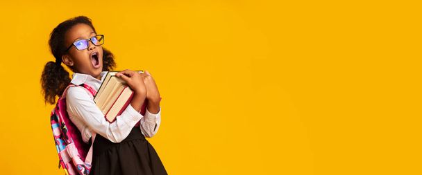 アフロ小学生の女の子あくび本、黄色の背景、パノラマ - 写真・画像
