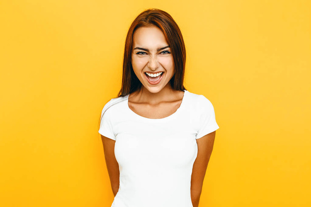 Young positive girl laughing on yellow background - Fotografie, Obrázek