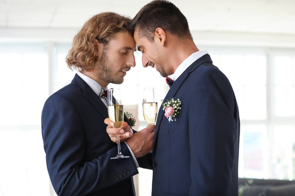 Happy gay couple with champagne on their wedding day at home - 写真・画像
