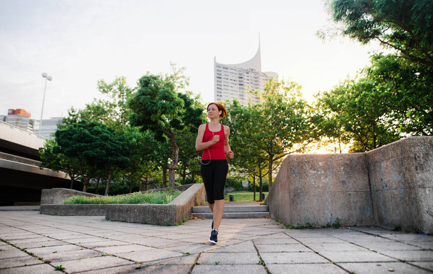 Young woman runner jogging outdoors in city early in the morning. - Foto, Imagem