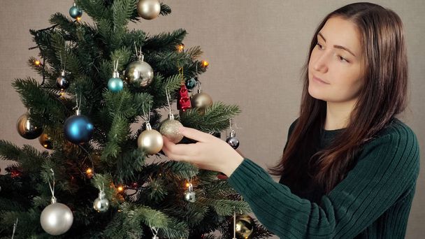 žena s volným účesu zdobí umělý vánoční stromek - Fotografie, Obrázek
