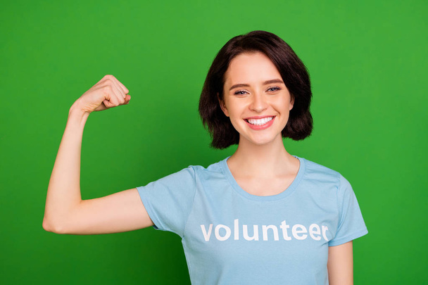 Close-up portrait of her she nice attractive cheerful glad content girl wearing blue t-shirt showing arm muscles world saver isolated over bright vivid shine vibrant green background - Fotografie, Obrázek