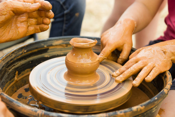 Una vista de cerca sobre el proceso de producción de cerámica en la rueda del alfarero con los niños. Artesanía de arcilla con concepto de niños
. - Foto, Imagen