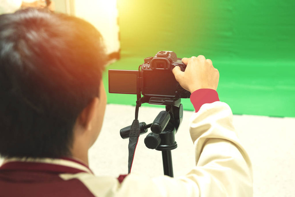 Videographer taking video camera, camera equipment film stand by on green screen. - Photo, Image