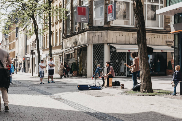 People walking past street musician on a street in Luxembourg Ci - Φωτογραφία, εικόνα