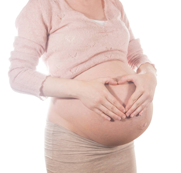 Pregnant woman profile holding hands protectively over belly - Foto, afbeelding