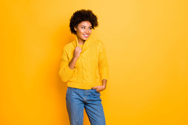 Foto van donkere huid grappige dame in goed humeur dragen warme gebreide Pullover en jeans staande geïsoleerde gele achtergrond - Foto, afbeelding
