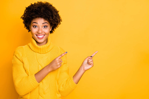 Closeup photo of dark skin sales lady indicating fingers empty space wear warm knitted pullover isolated yellow color background - Photo, image
