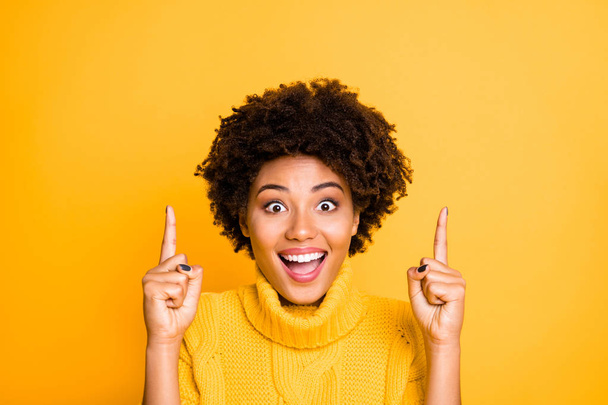 Visit our final sale. Photo of dark skin lady indicating index fingers up empty space on low prices placard wear warm knitted jumper isolated yellow background - 写真・画像