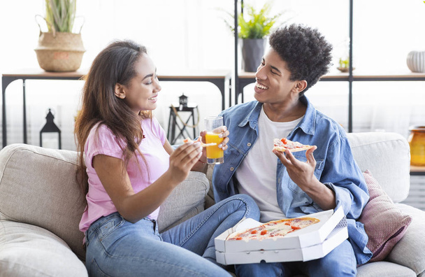 Felice coppia africana mangiare pizza e bere qualcosa a casa
 - Foto, immagini