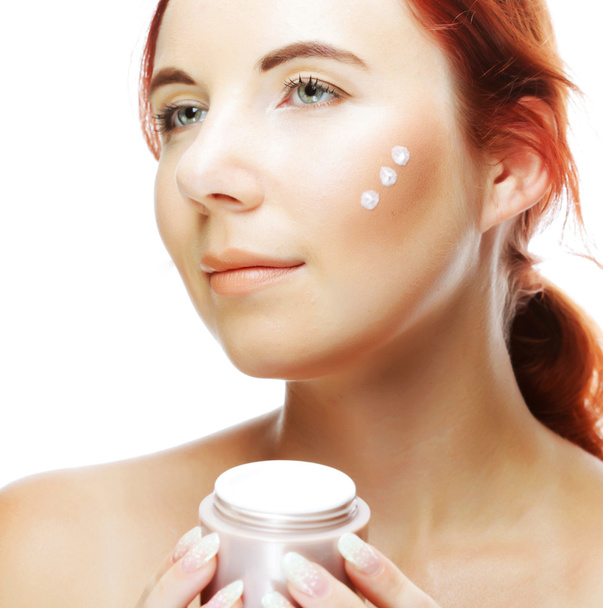 Young smiling woman applying cream on her face - Photo, Image