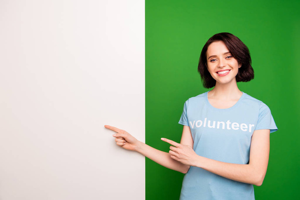 Portrait of her she nice attractive cheerful confident girl wearing blue t-shirt pointing two forefingers aside at copyspace advert solution isolated over bright vivid shine vibrant green background - Φωτογραφία, εικόνα