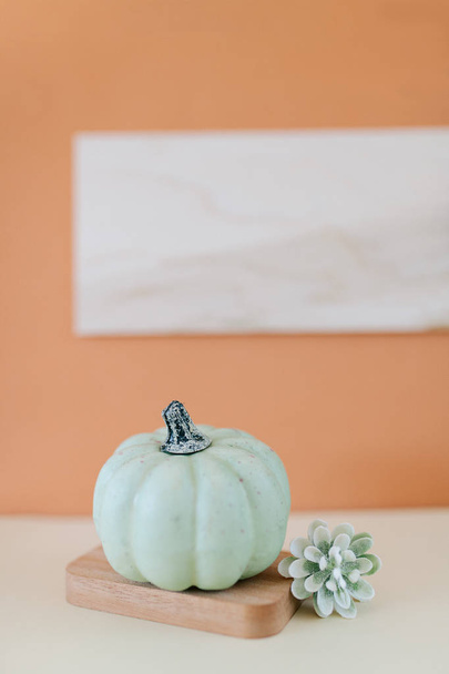 Teal and cream small pumpkins on layered wooden tray and orange background. Side view. - Zdjęcie, obraz
