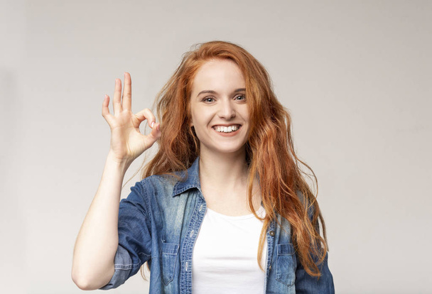 Positieve Redhead meisje toont OK teken en glimlachend naar camera - Foto, afbeelding