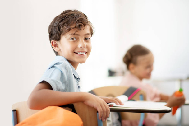 Dark-eyed boy smiling while having little break at school - Foto, Bild