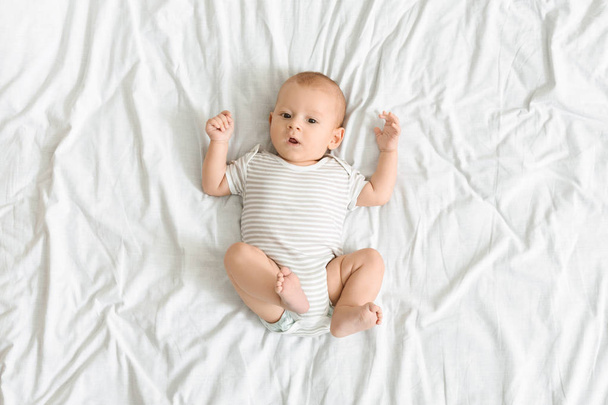 Curious baby lying on bed and looking to camera - Photo, Image