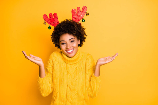 I will be Rudolf in 2020 Photo of charming lovely with toothy smile girl shrugging shoulders having good mood demonstrating her newyear time traditional red horns on head isolated background - Foto, afbeelding