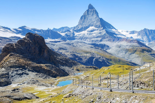 paisagem magnífica nos Alpes suíços, em primeiro plano uma ferrovia, no fundo uma montanha Matterhorn
 - Foto, Imagem