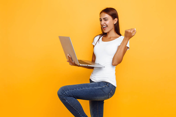 Portrait of excited young girl holding laptop and celebrating su - Photo, Image