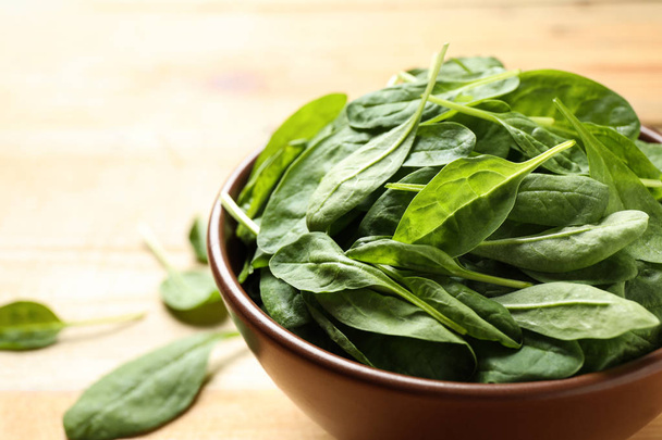 Bowl of fresh green healthy spinach on wooden table, closeup - Fotografie, Obrázek