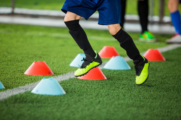 Kid soccer players jogging between marker cones on green artific - Photo, Image
