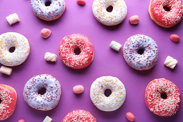 Different tasty donuts with candies on color background - Fotoğraf, Görsel