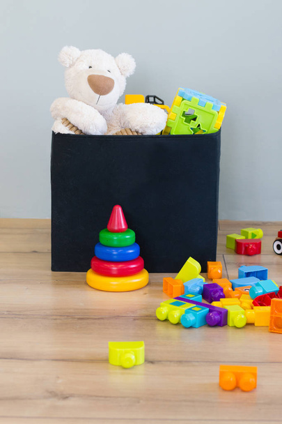 Brinquedos infantis em caixa e no chão
 - Foto, Imagem