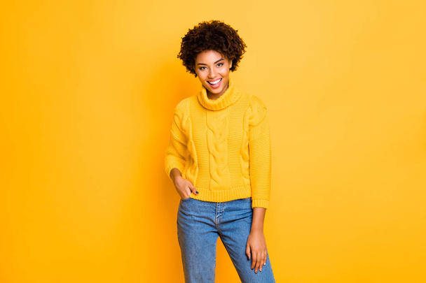Photo of dark skin funny lady in good mood wear warm knitted pullover and jeans standing isolated yellow background - Foto, imagen