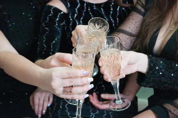 Świąteczne kieliszki z szampanem w kobiecych rękach. Uroczystości świąteczne, urodziny, wieczór panieński, ślub - Zdjęcie, obraz