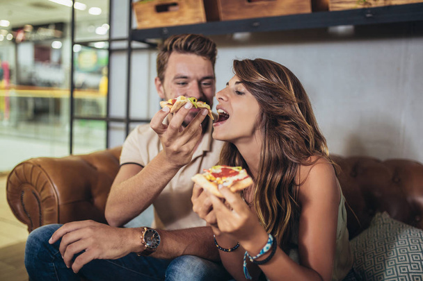 Kuva nuoresta onnellisesta parista syömässä pizzaa ravintolassa
 - Valokuva, kuva
