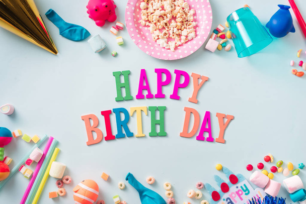 Happy birthday background or greeting flyer. Colorful holiday supplies on blue table top view. Flat lay style. - 写真・画像