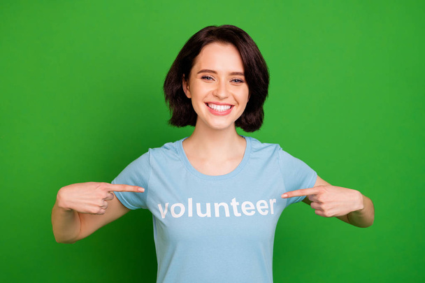 Close-up portrait of her she nice attractive lovely cheerful cheery girl wearing blue t-shirt pointing at herself volunteer organization isolated over bright vivid shine vibrant green background - Photo, image