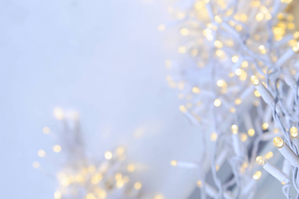 A white garland with flickering yellow lights weighs outside on a background of snow.  - Photo, Image