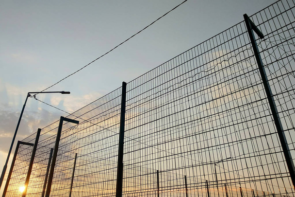 Mavi gökyüzü arka plan üzerinde sınırlı alanda yüksek tel örgü çit. - Fotoğraf, Görsel