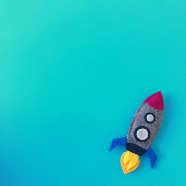 Teal achtergrond met handgemaakte vilt Rocket Toy - Foto, afbeelding